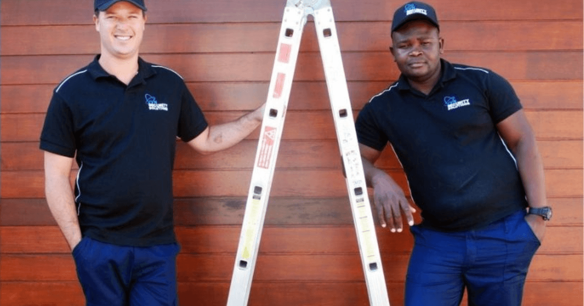 Two JVN Security Solution employees leaning on a ladder 