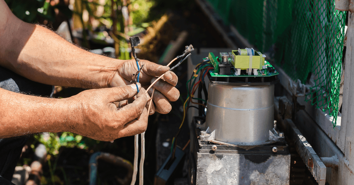 A man doing maintenance on a automated gates control board