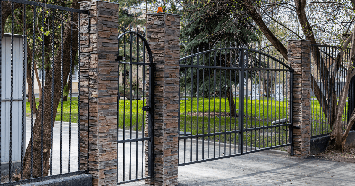 Secured gated entrance with steel fencing surrounding a residential property