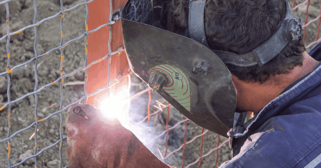Professional welder fabricating a steel fence during installation