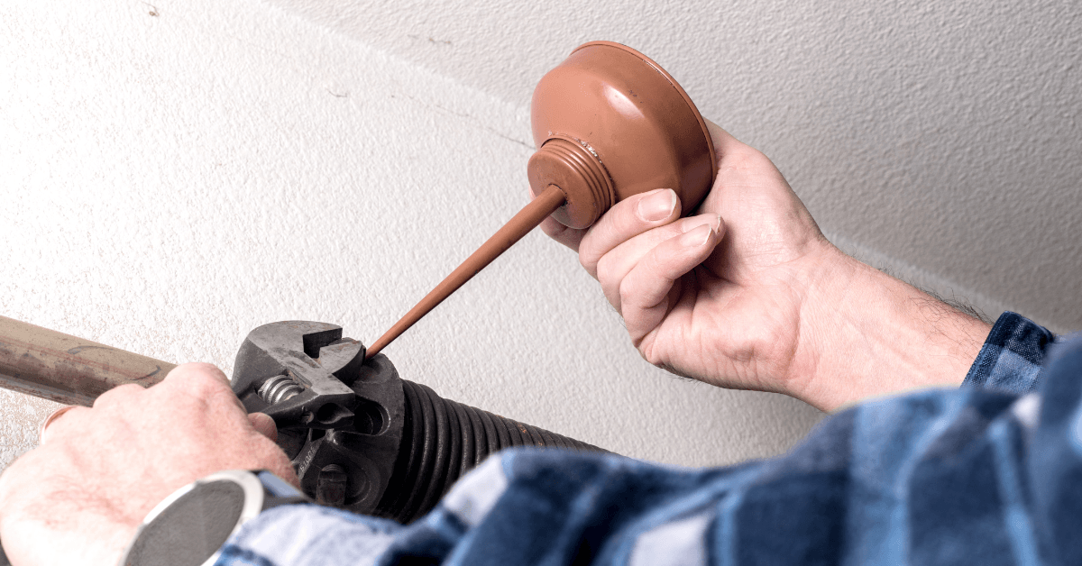 Technician lubricating garage door springs
