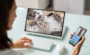 Person checking camera footage on phone and laptop